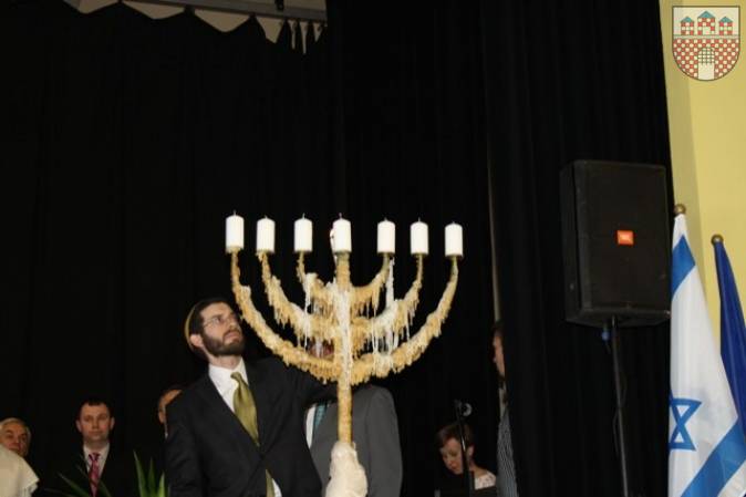 :  Rabin Gminy Wyznaniowej Żydowskiej Joshua Ellis odpala świecę na menorze.